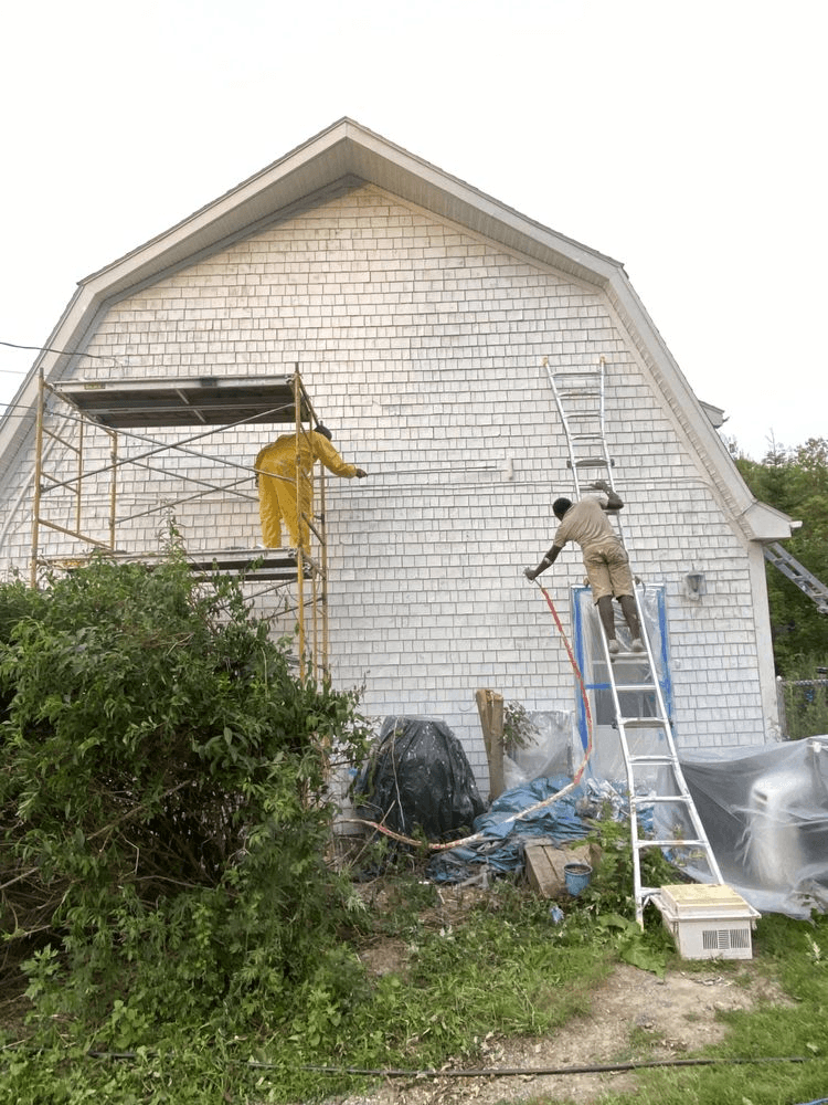 Two people, powerwashing a house